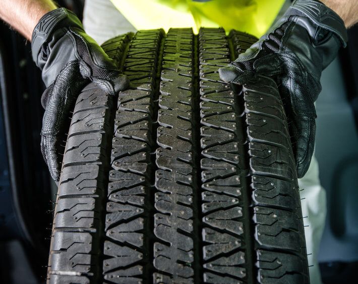 Gloved hands examining surface of tire