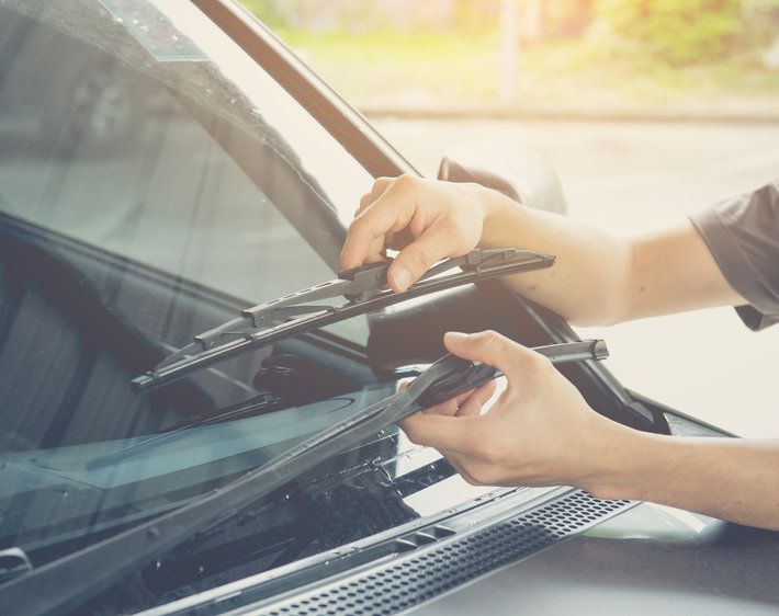 Hand picking up windscreen wiper on car and checking rubber, checking to see whether wipers need to be replaced