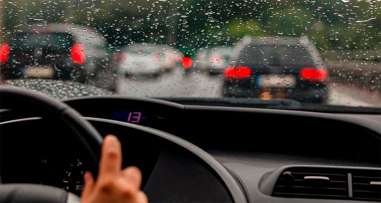 tablero de un automóvil y parabrisas con gotas de lluvia