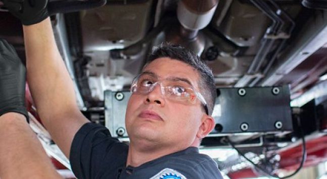 A technician wearing goggles inspecting a vehicle.