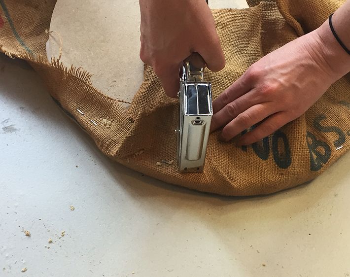 Stapling and folding burlap over plywood to make ottoman cushion