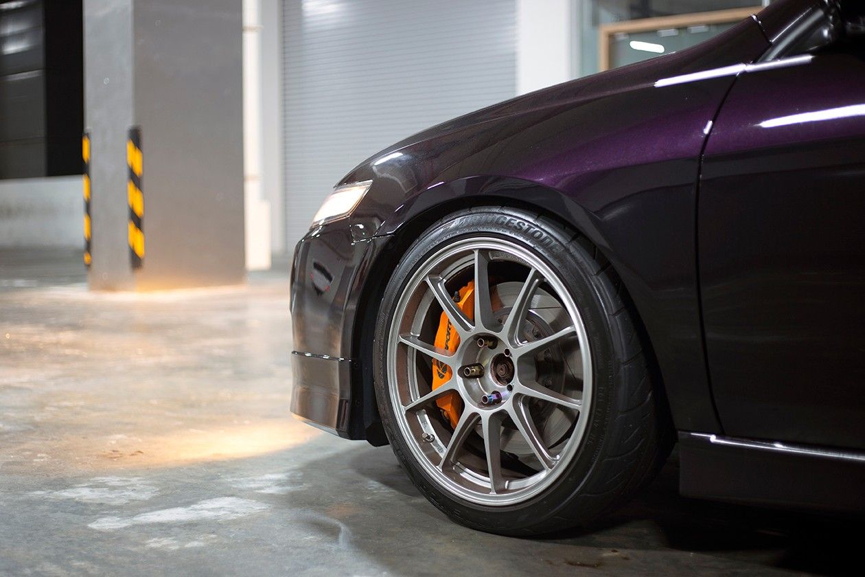 Driver side tire of purple vehicle in parking garage.