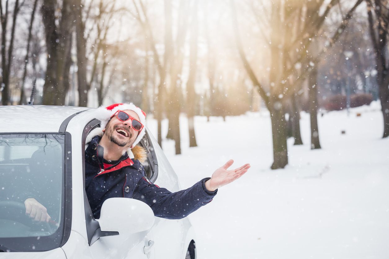 man driving car while wearing a santa hat