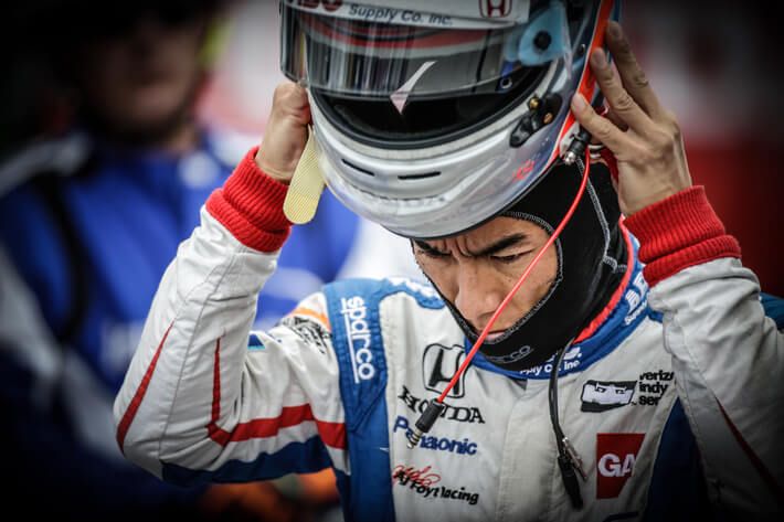 INDYCAR driver putting on his helmet, preparing for race