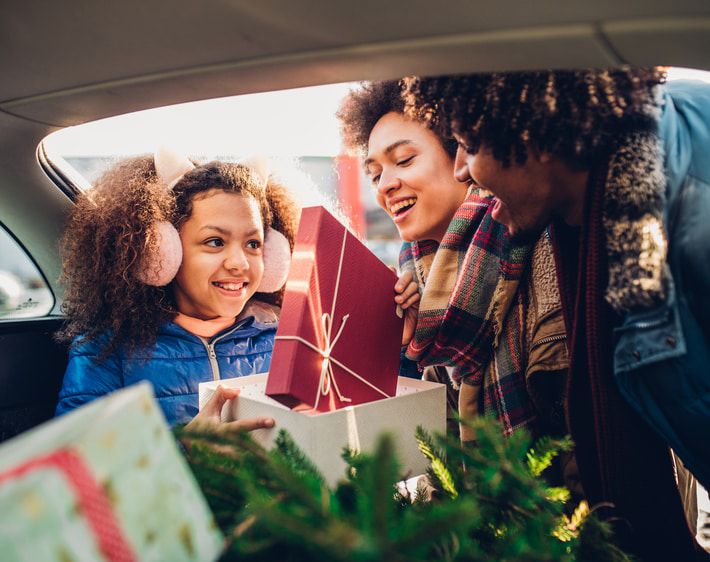 Family loading holiday gifts into a trunk