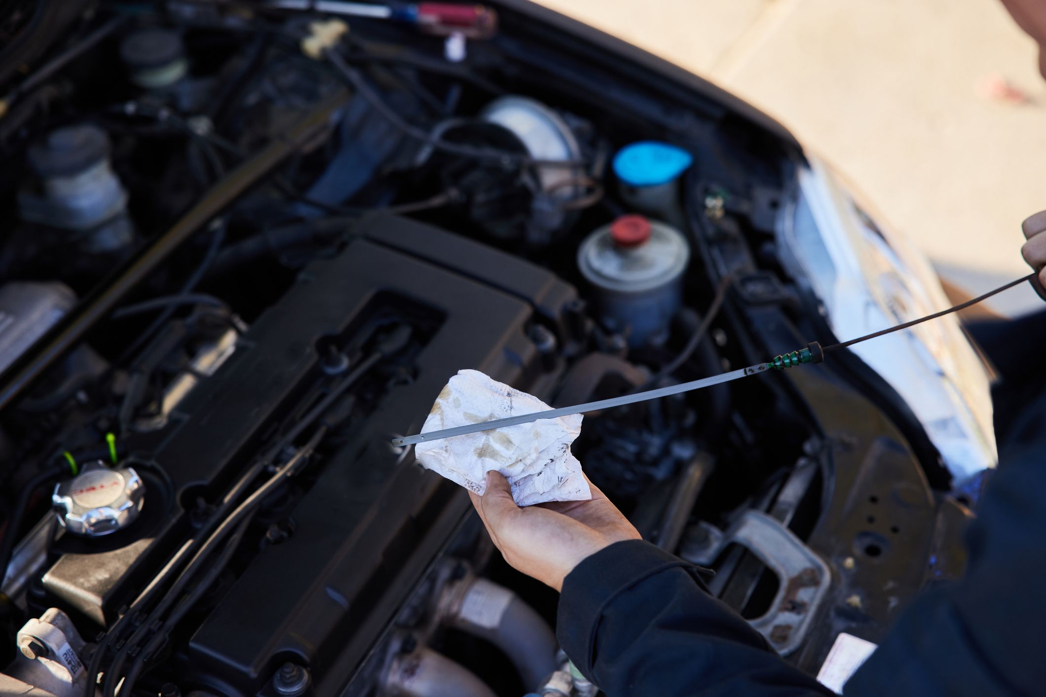 mechanic checking the oil of a car with a-ipstick