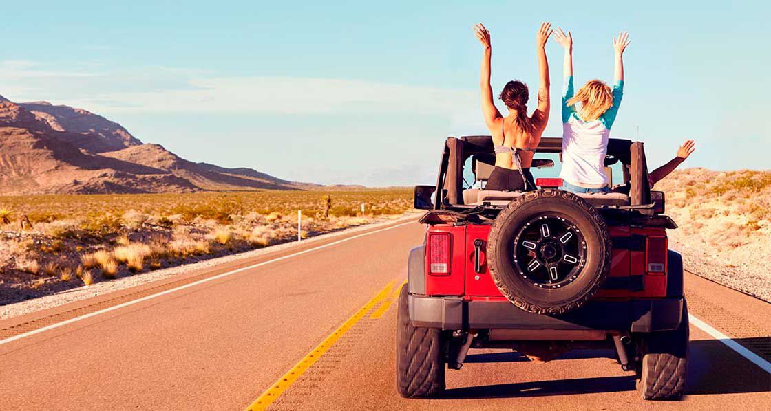 camioneta jeep con 4 personas en una carretera desértica en dirección a un festival de música