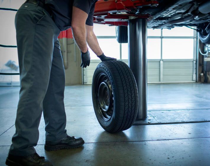 firestone technician rolling a tire for repair