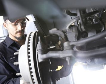 Skylar, a Firestone technician performs a brake service wearing grey overalls