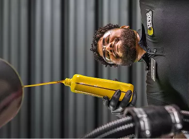 A technician pouring motor oil into the top of an engine.