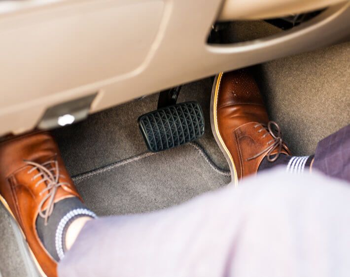 Businessman's feet in wheel well, pressing gas and brake pedal