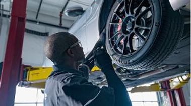 An expert technician working on the tire of a raised car.