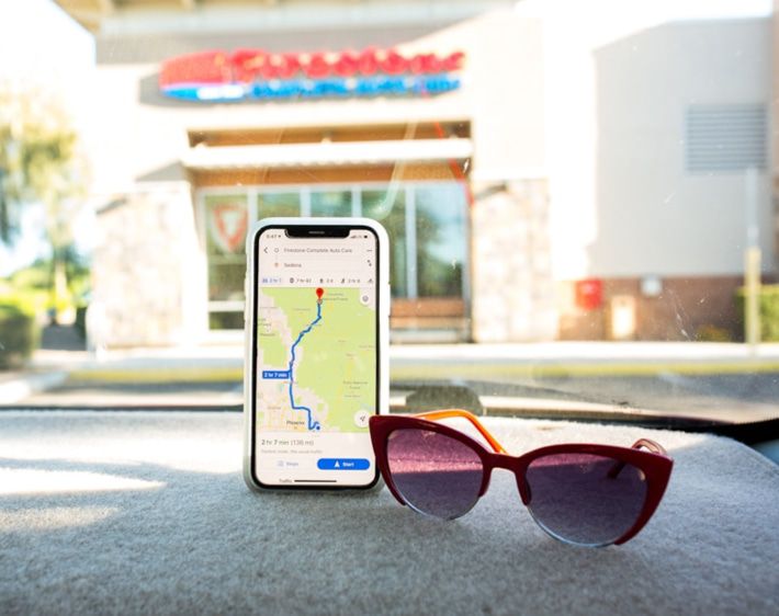 iPhone maps and sunglasses on a car dashboard
