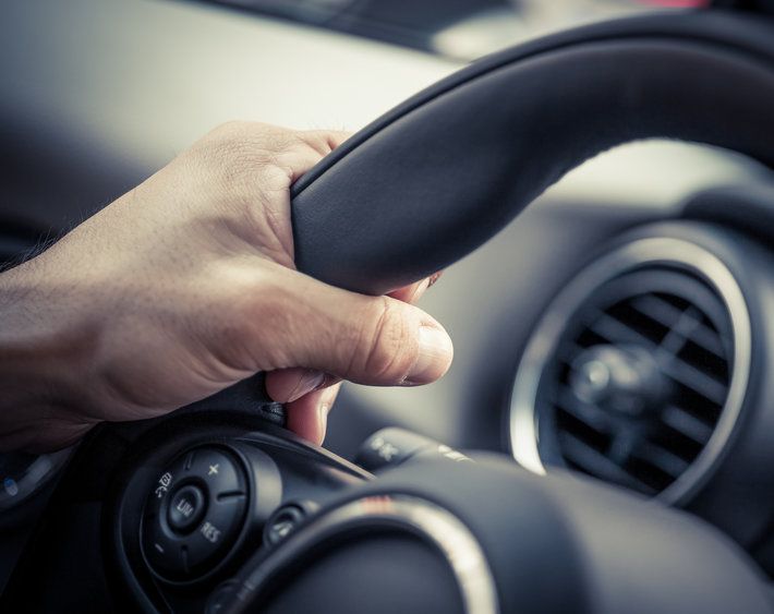 Hand gripping car's steering wheel