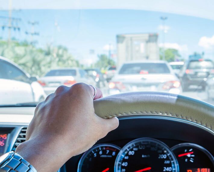 Man's hand on steering wheel, navigating traffic