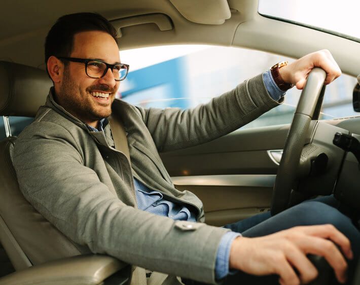 Smiling man driving a Nissan Altima