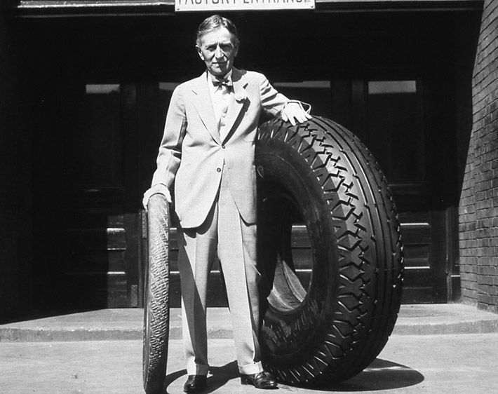 Harvey S. Firestone with an original non-skid tire and an oversized tire, date unknown.
