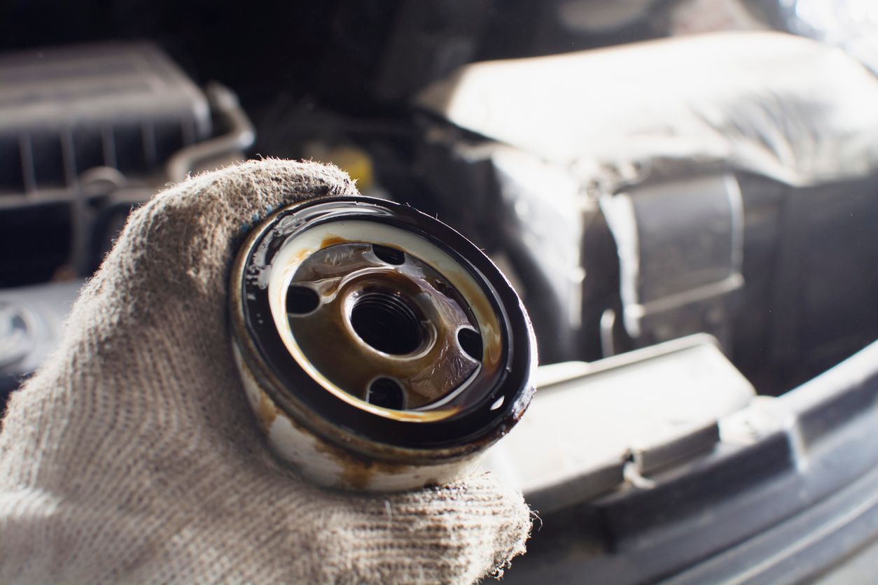 a man in a glove holds an old oil filter