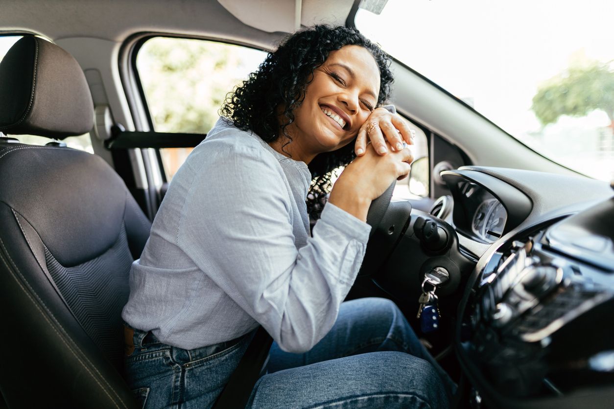 Young and cheerful woman enjoying her new car