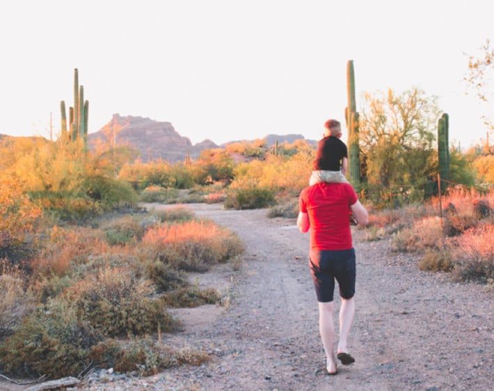 Kid on dad's shoulders on a desert road