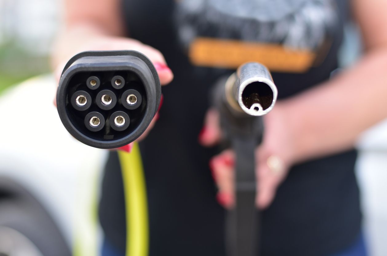 Fuel nozzle and electric car charger plug in hands