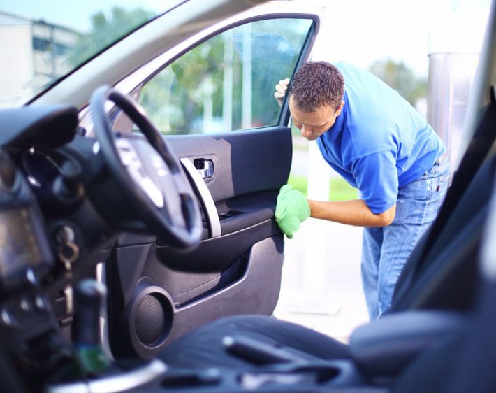 Man wiping down the inside of a car door