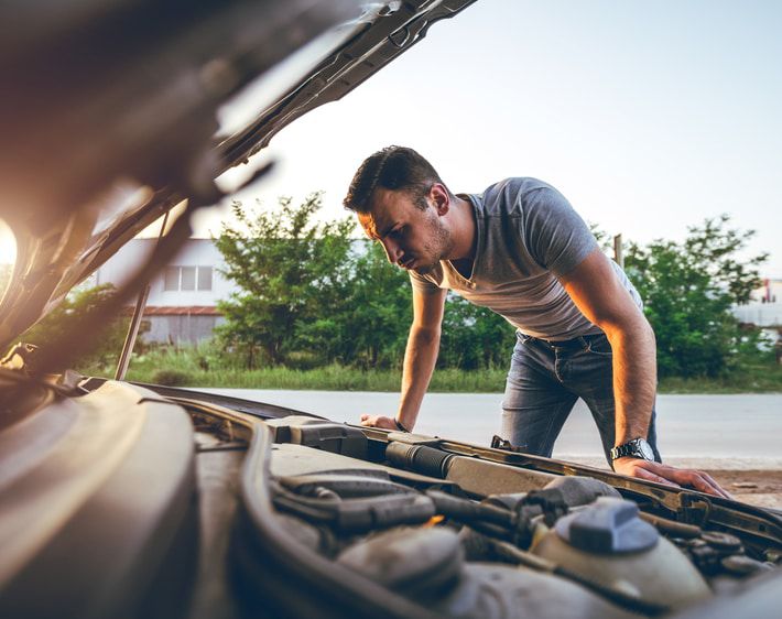 Man inspecting underneath car hood