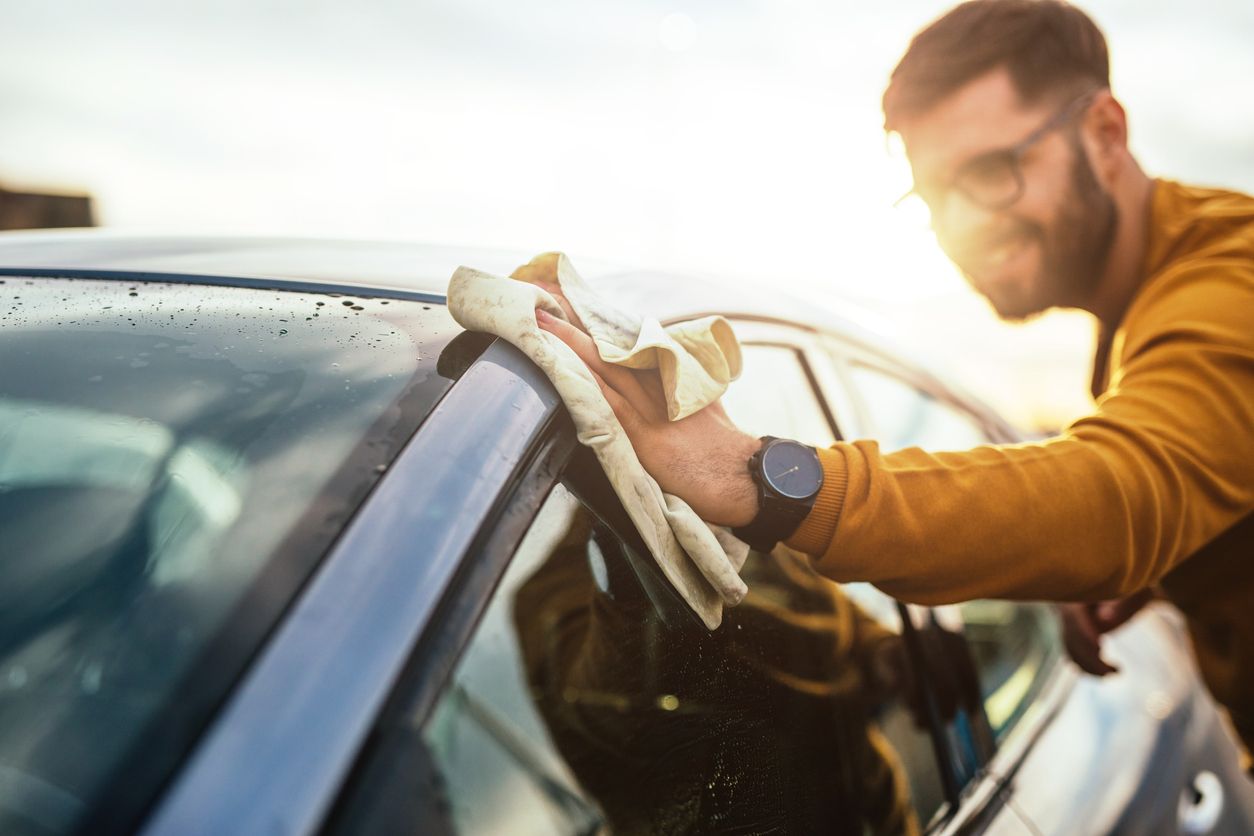 image of man wiping down car