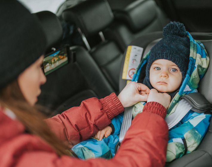 Mom buckling child into carseat