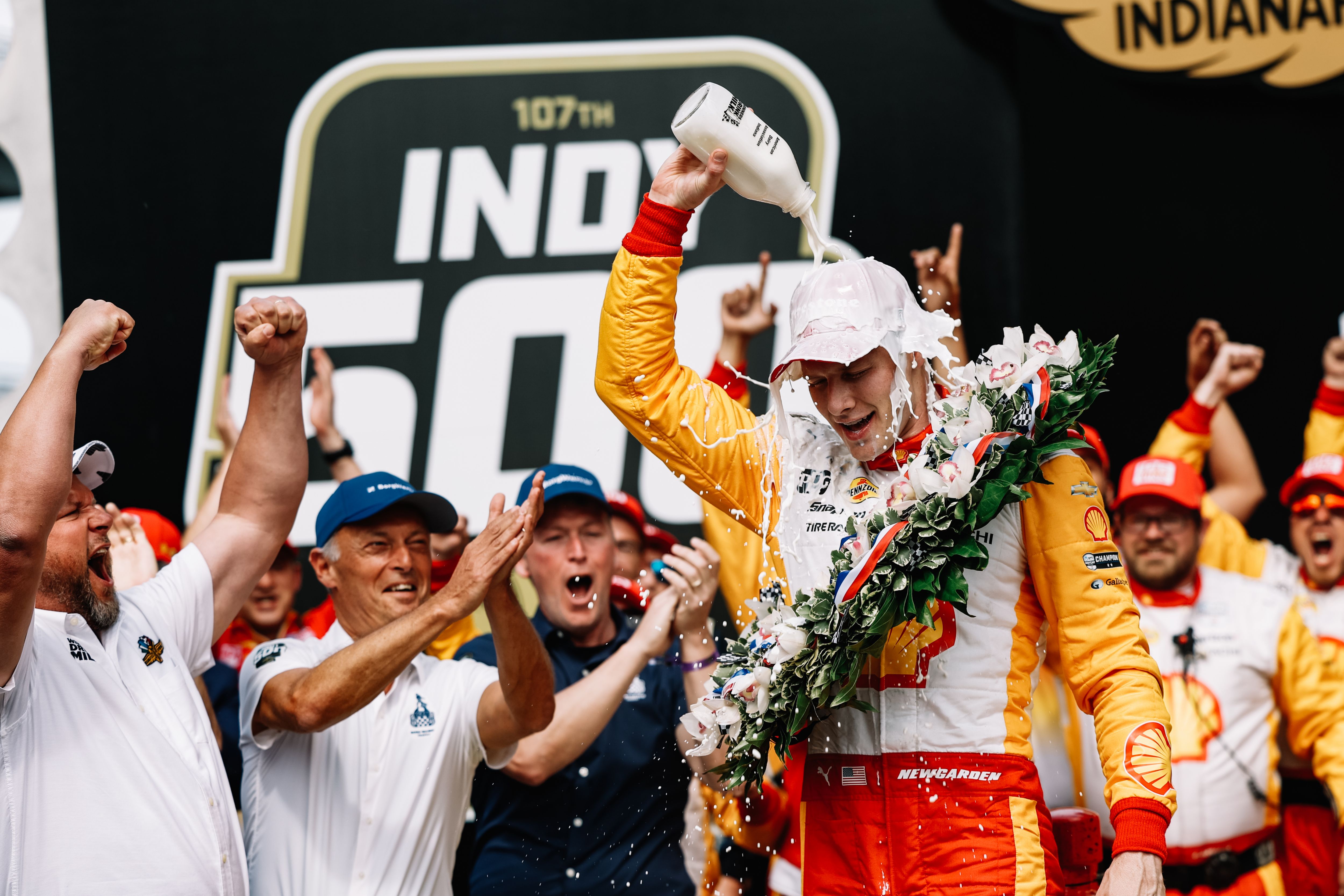 Josef Newgarden — winner of the 107th Running of Indianapolis 500 — smiling and pouring milk over his own head.