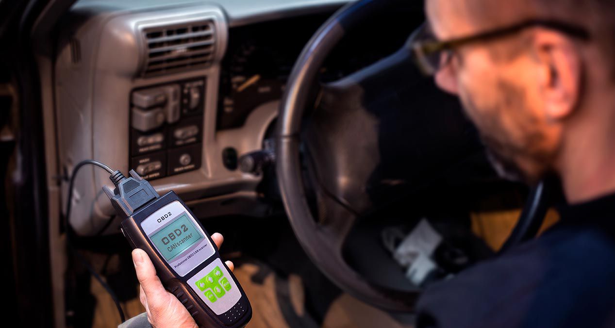 Técnico conectando el lector de emmiciones en el puerto OBD2 de un auto