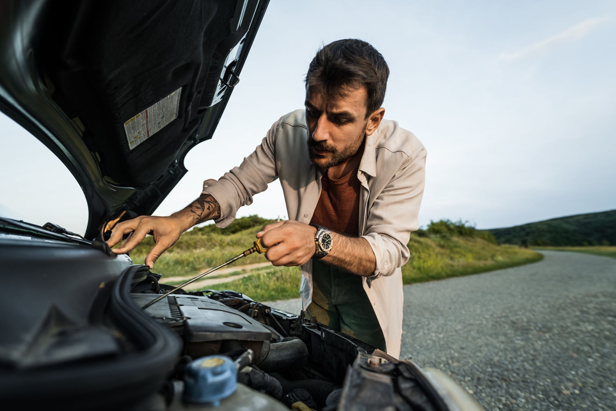 man haveing car problems and checking oil level 