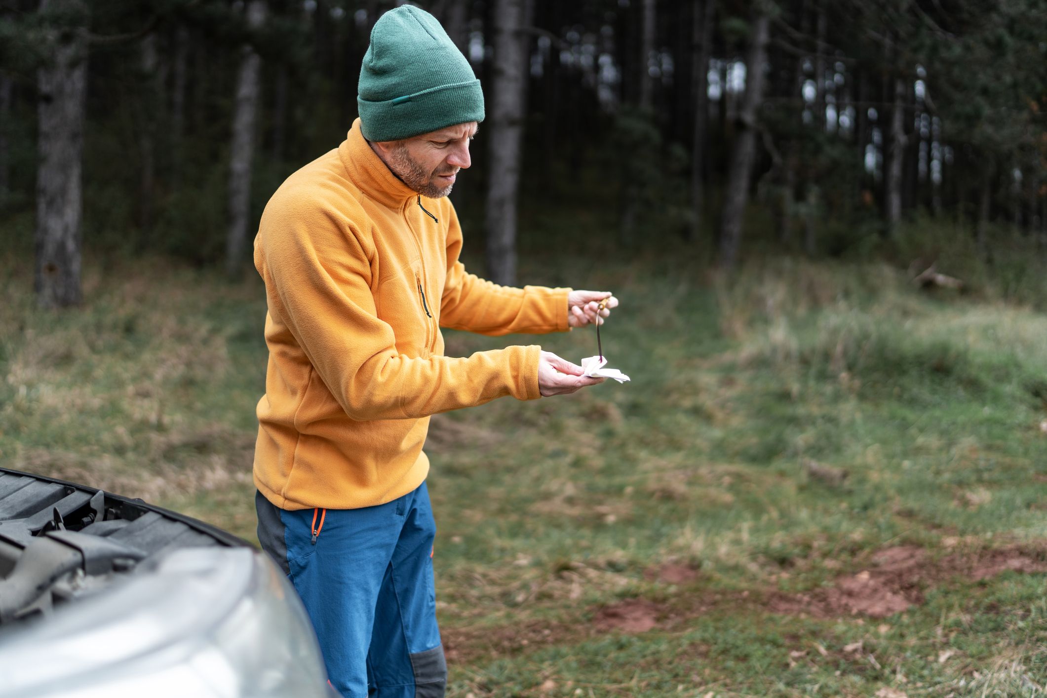 man chaning car oil level with dipstick