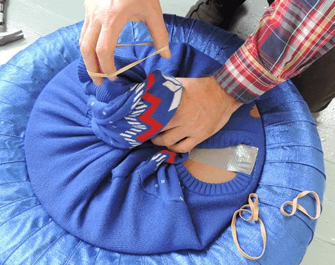 Securing excess sweater fabric with rubber band at the back of the tire