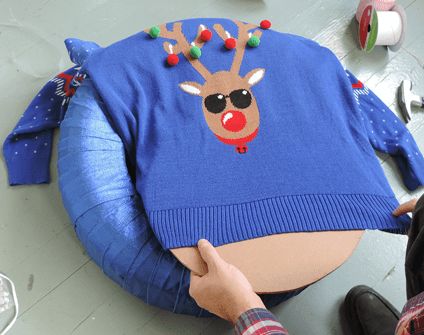 Pulling holiday sweater with reindeer on it over circular piece of cardboard