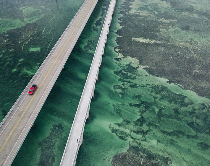 red car on a highway crossing the ocean