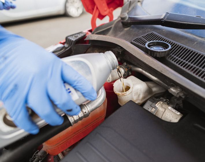 Person pouring brake fluid into car