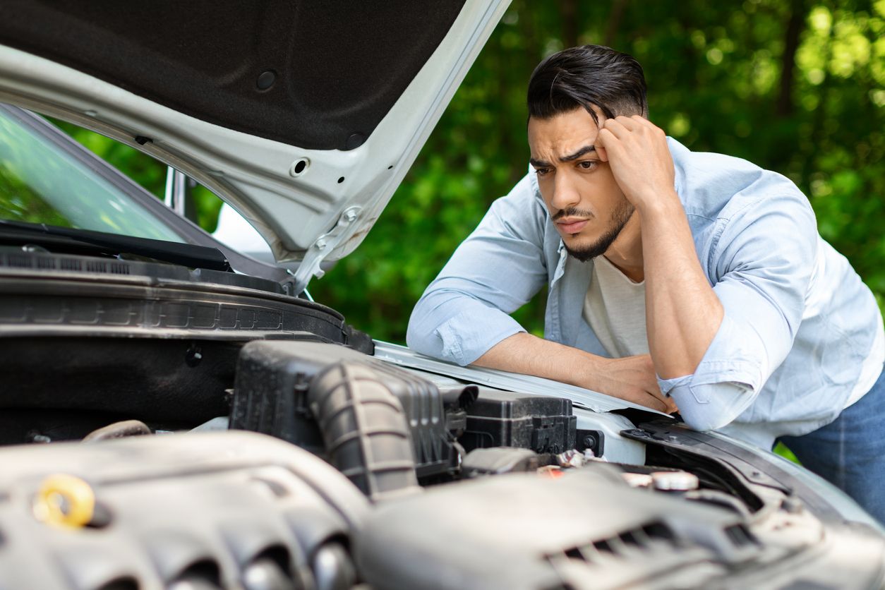 image of a confused man looking at his car engine