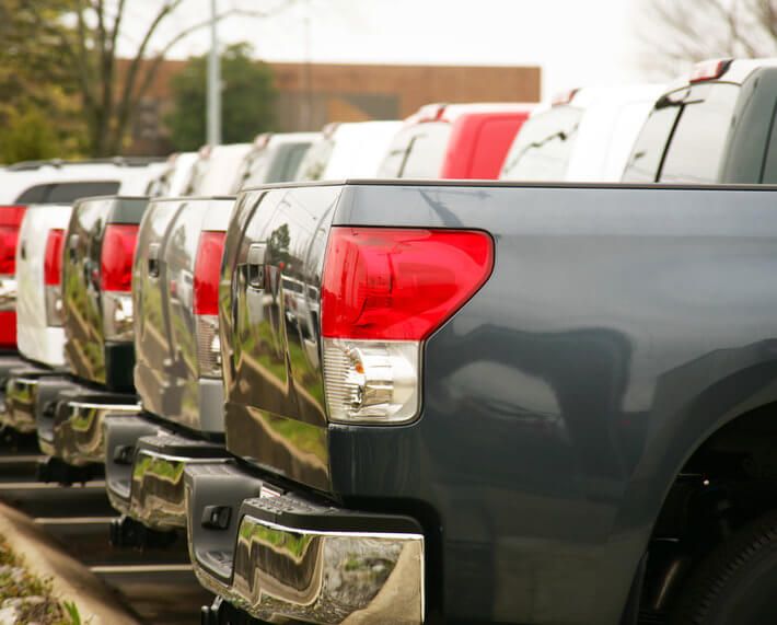 Row of new trucks for sale, with focus on the bed of the trucks