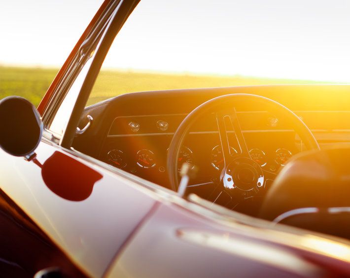 Retro red car stay on asphalt road at sunset