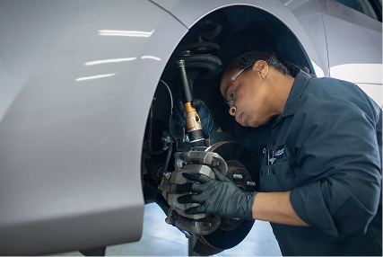 A technician adjusting wheel components on a raised vehicle.