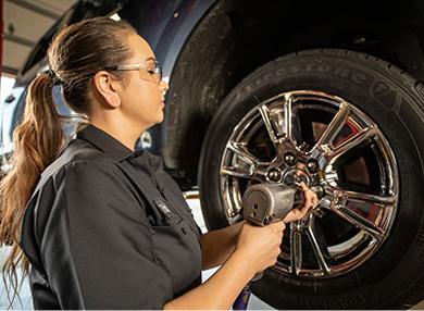 A technician adjusting wheel fasteners of a car.