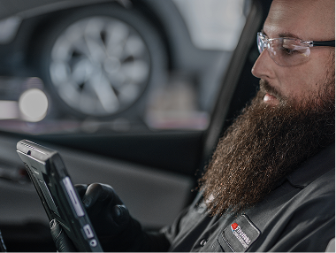 Technician with a beard looking a tablet.
