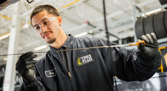 A technician checking an engine dipstick.