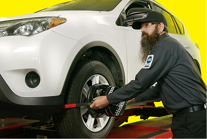 A technician checking wheel and tire alignment on a CUV.