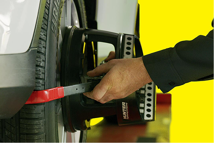 A technician checking wheel and tire alignment.