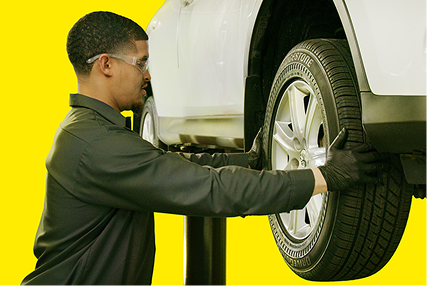 A Tires Plus technician checking the condition of a tire.