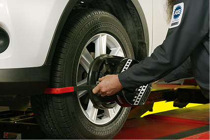 A technician checking wheel and tire alignment.
