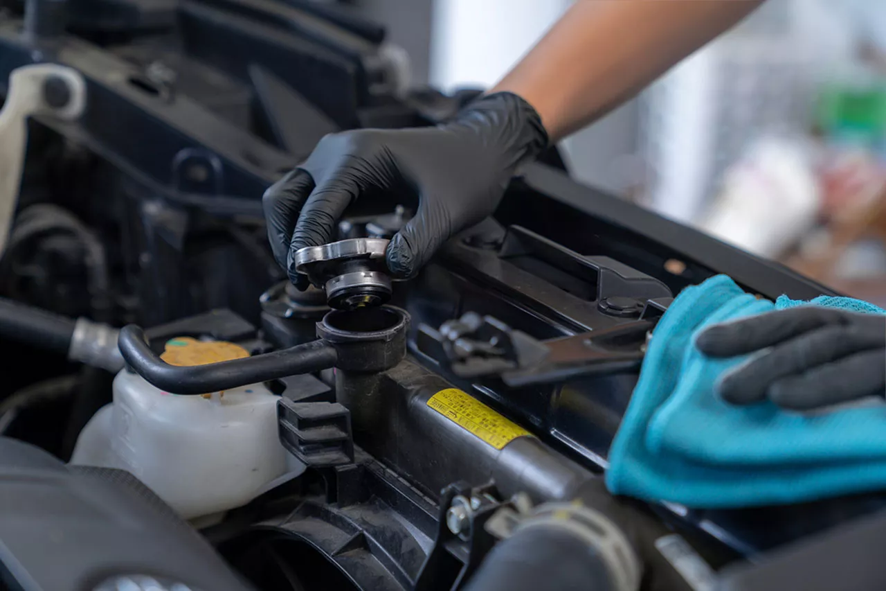 Close up of a technician checking coolant into a radiator.