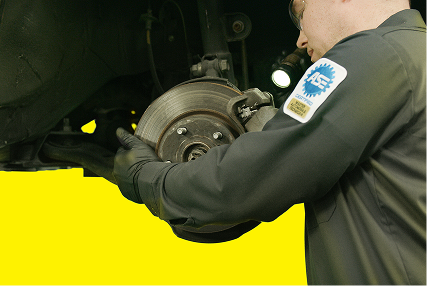 A technician inspecting brake components with a flashlight.